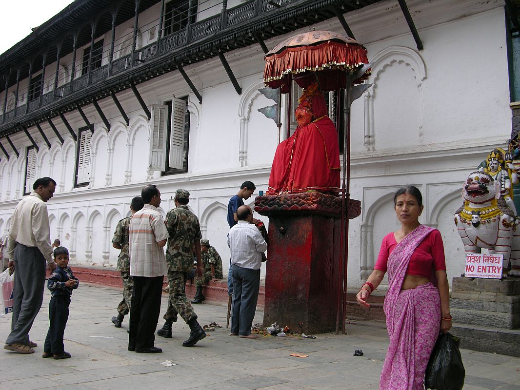 Kathmandu Durbar Square 06 02 Hanuman Statue The Hanuman (1672) statue stands at the entrance to the Hanuman Dhoka palace in Kathmandu Durbar Square. The Hindu god Hanuman is depicted as a monkey, and sits on a tall stone pedestal, cloaked in red and sheltered by an umbrella. Standards bearing the double-triangle flag of Nepal flank the statue. I watched the devout Hindus circle the statue, touching their foreheads on the Hanuman pedestal.